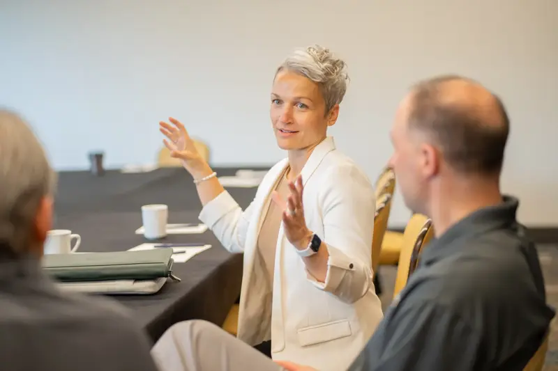 Person sitting at table speaking with arms open