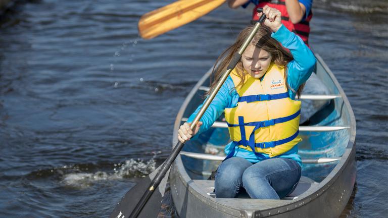 an preteen girl learning to canoe on one of the many rivers and lakes in Minnesota